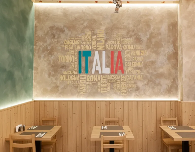 Textured beige feature wall with Italian city word‑cloud mural in a modern Italian restaurant interior.