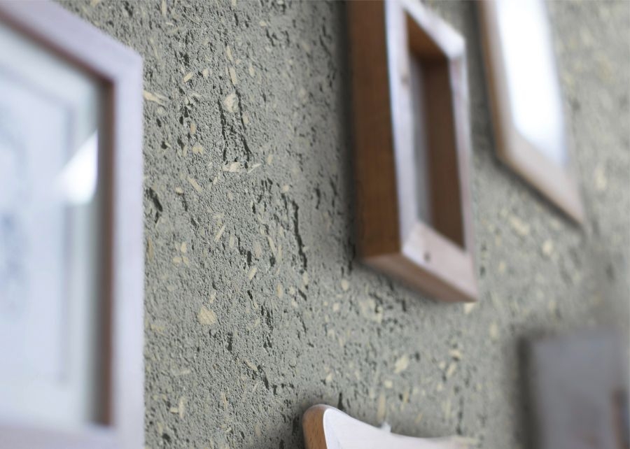  
“Close‑up of a textured clay‑finish wall with embedded natural particles, decorated with wooden picture frames in different sizes and tones. The rough, earthy plaster surface contrasts with the smooth wooden frames, creating a warm, handcrafted interior look.